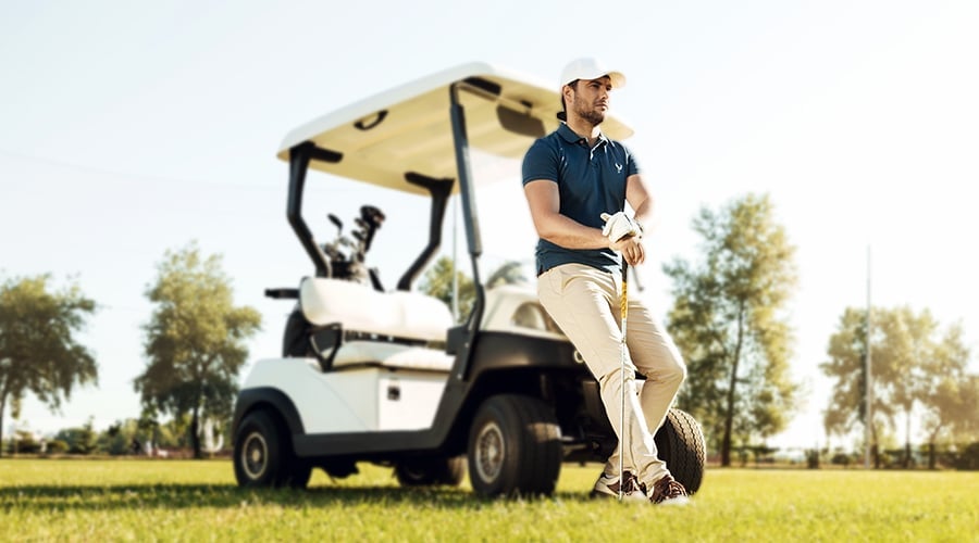 Golfer ruht sich neben seinem Buggy aus