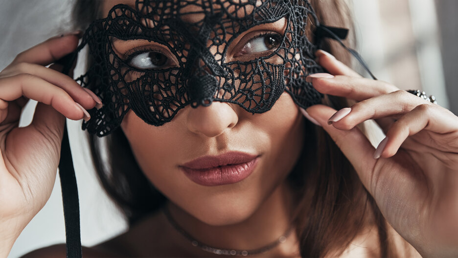 Primer plano de una mujer ajustándose un antifaz de encaje negro para Halloween en Marbella.