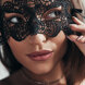 Primer plano de una mujer ajustándose un antifaz de encaje negro para Halloween en Marbella.