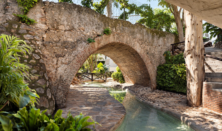 Histórico arco de piedra sobre un canal de jardín, un pintoresco recuerdo de la historia de Marbella.
