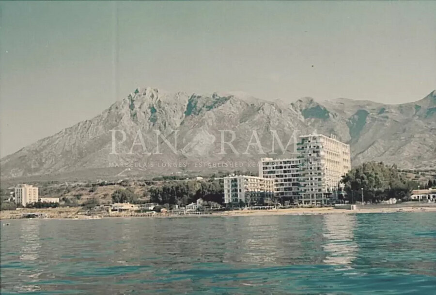 Fotografía antigua de edificios frente al mar bajo La Concha, capturando un capítulo de la historia de Marbella.
