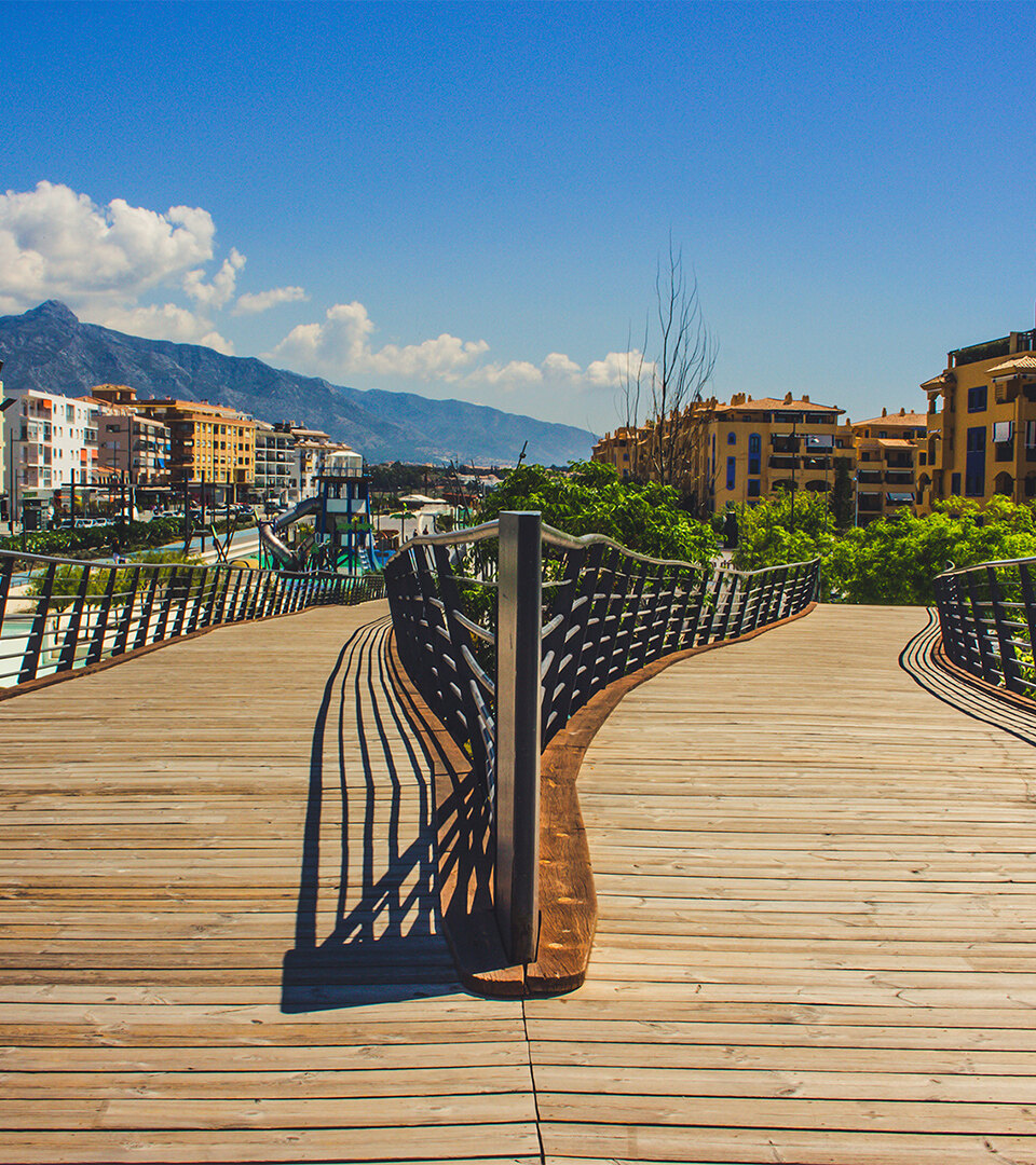 Modern boulevard footbridge in San Pedro de Alcántara with La Concha mountain in the background, reflecting the contrast between urban renewal and san pedro history.
