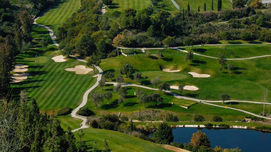 Golf course in Marbella surrounded by landscaped greens, lakes and sand bunkers