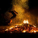 Escena tradicional de salto sobre el fuego con brasas incandescentes y chispas iluminando la Noche de San Juan en Marbella.