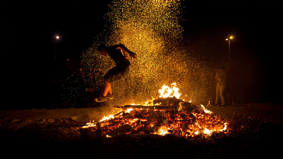 Scène traditionnelle de saut au-dessus du feu avec des braises rougeoyantes et des étincelles illuminant la nuit de la Saint-Jean à Marbella.