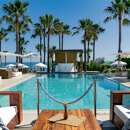 Exclusive beach clubs in Marbella with a pool, white loungers, palm trees and panoramic Mediterranean views