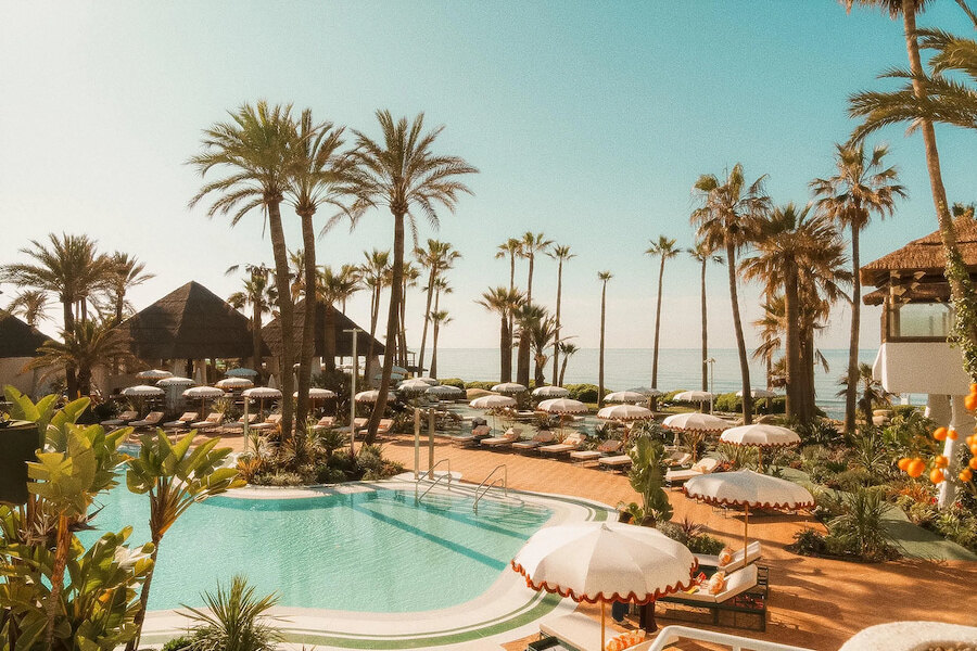 Elegant beach clubs in Marbella with palm trees, poolside loungers and sea views on the Mediterranean coast