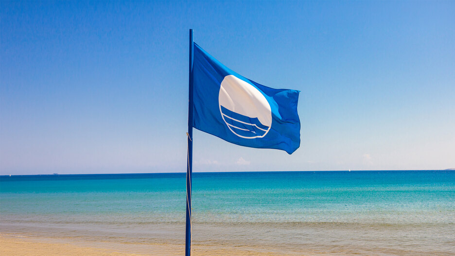 Blue Flag die wappert aan zee, als symbool van de kwaliteit en excellentie van de Blue Flag-stranden in Málaga.