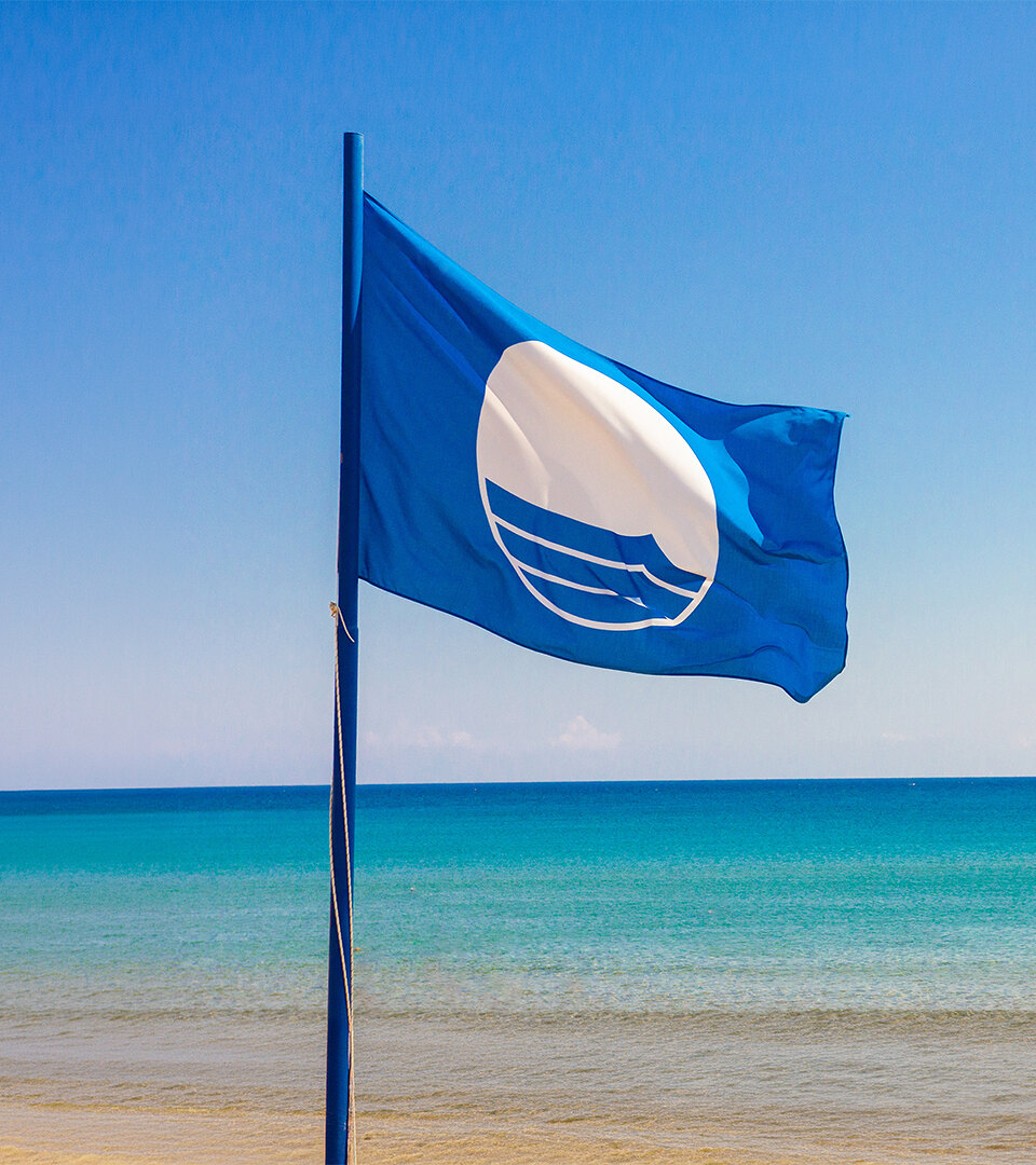 Blue Flag flying by the sea, symbolising the quality and excellence of Blue Flag beaches in Málaga.