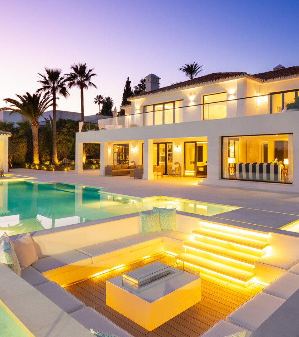 Villas en venta en el sur de España con una piscina iluminada, salón exterior y elegante terraza al atardecer.
