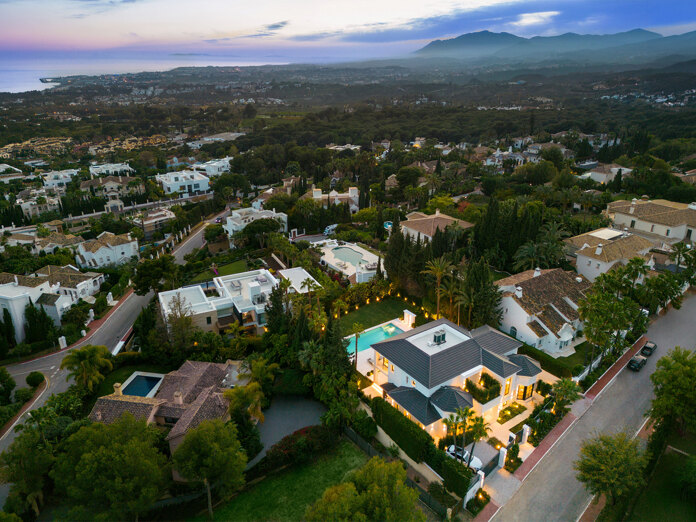 Aerial view of an exclusive residential area in Marbella with luxury villas, sea views and mountain backdrop
