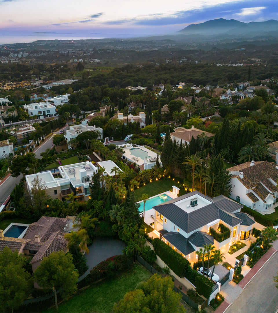 Aerial view of an exclusive residential area in Marbella with luxury villas, sea views and mountain backdrop