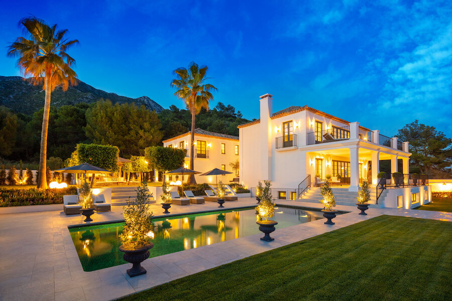 Classic luxury villa in Marbella with illuminated terraces, landscaped gardens and mountain views at twilight