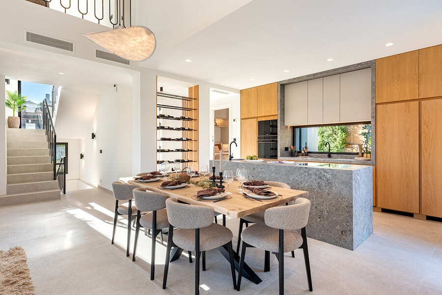 Open-plan dining and designer kitchen inside a turnkey home in Marbella with natural wood and stone finishes.