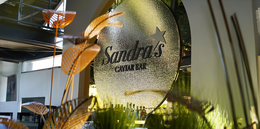 An illuminated Sandra’s Caviar Bar sign inside the Starlite Marbella 2026 venue, surrounded by elegant interior details.
