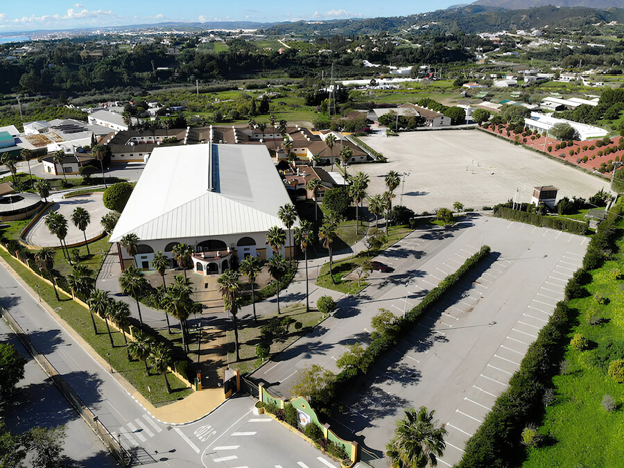 Vista aérea de una instalación ecuestre dedicada a la equitación en Marbella con pistas, establos y el paisaje circundante.