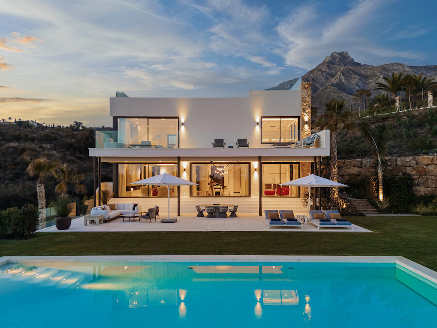 Modern hillside villa in Marbella with large pool, outdoor lounge areas and panoramic mountain views at sunset