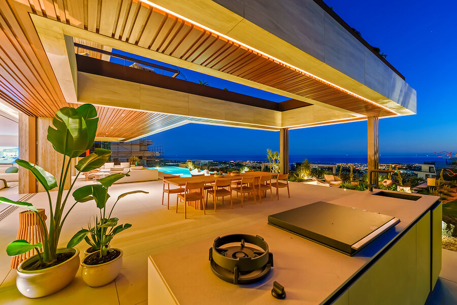 Evening terrace of a turnkey home in Marbella with outdoor kitchen, dining area and panoramic sea views.
