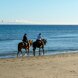 Tranquila equitación en Marbella con dos jinetes disfrutando de un paseo por la playa junto a la orilla.