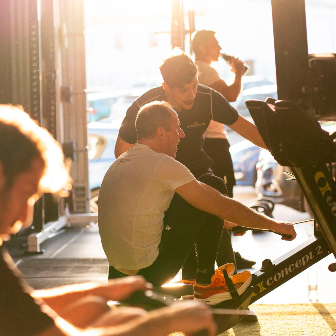 Coach unterstützt Mitglieder bei einem Ruder-Workout in einem der Luxus-Fitnessstudios in Marbella.