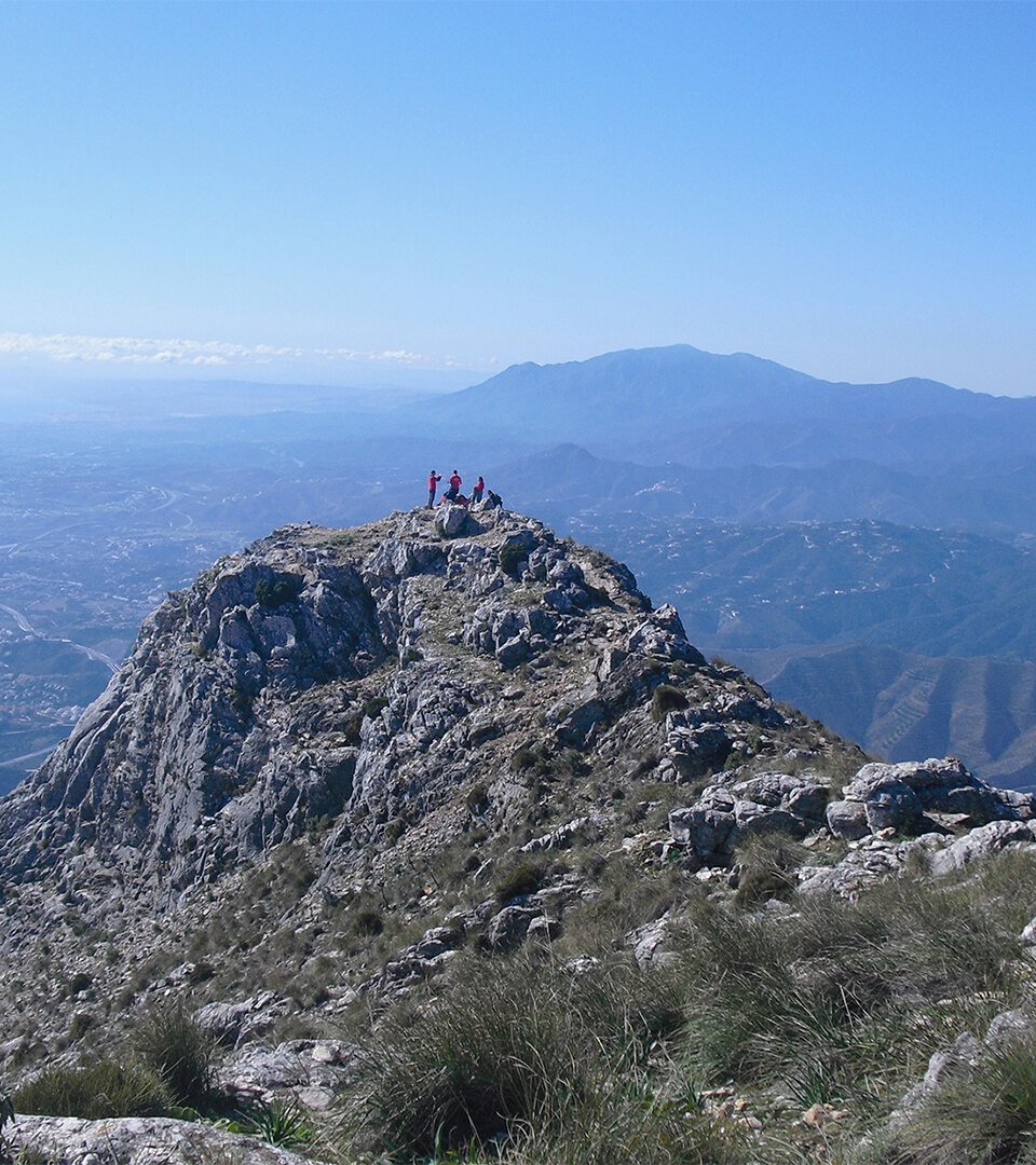 Wandelaars verzamelen zich op de rotsachtige top van La Concha boven het berglandschap van Marbella.