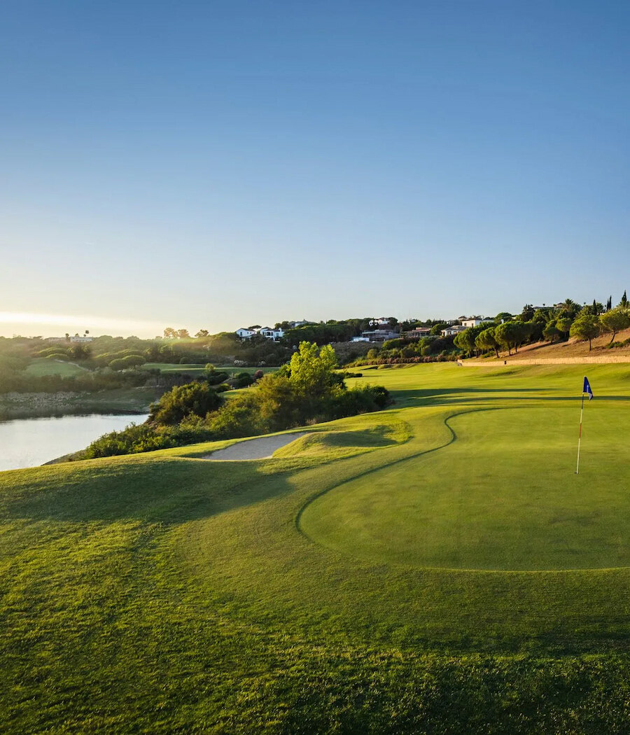 Sotogrande Spa and Golf Resort, locatie voor golftoernooien 2026–2027, met een green aan het meer bij zonsondergang.