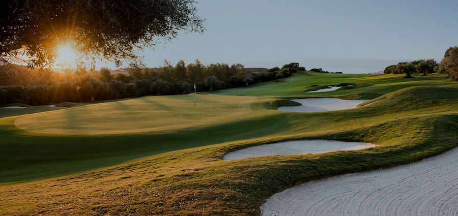 Golfbaan van Finca Cortesin in Casares, met zonovergoten greens, glooiende fairways en witte zandbunkers.