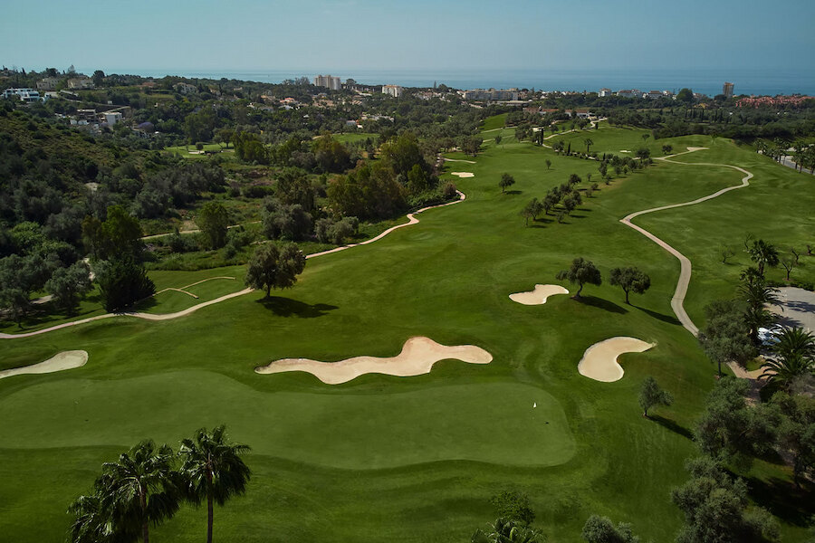 Luchtfoto van de golfbaan van Higuerón aan de Costa del Sol, met fairways, bunkers en uitzicht op de Middellandse Zee.