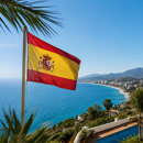 Spanish flag overlooking the Mediterranean coast, palm trees and villas, reflecting the quality of life in Spain.