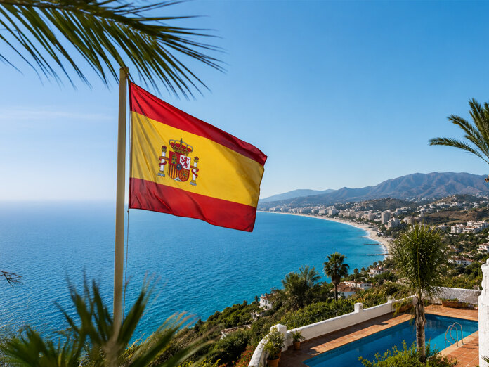 Spanish flag overlooking the Mediterranean coast, palm trees and villas, reflecting the quality of life in Spain.