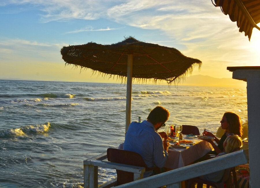 Sunset dinner by the sea with diners enjoying a coastal meal, a beautiful example of seafood restaurants in Marbella.