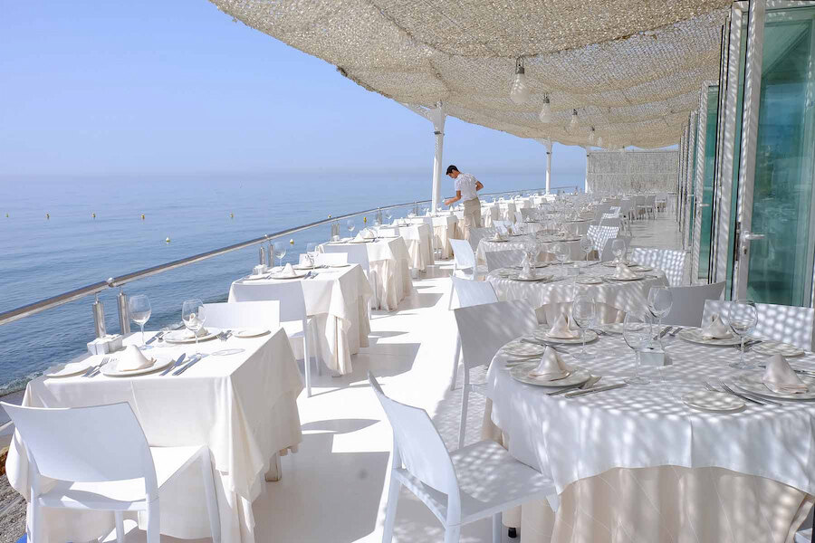 Elegant seaside terrace with white table settings and panoramic Mediterranean views, capturing the atmosphere of seafood restaurants in Marbella.