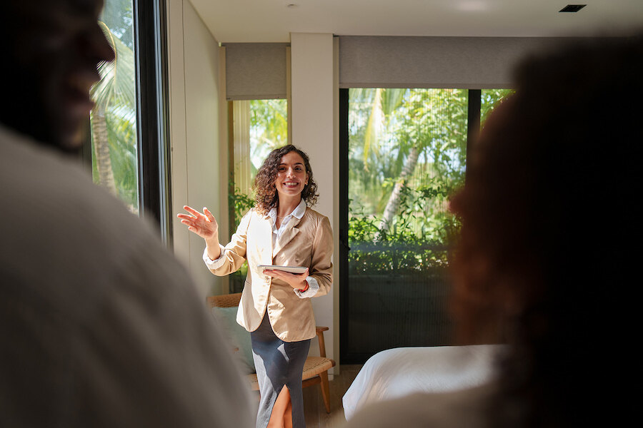 Real estate agent showing a bright luxury bedroom to clients during a private property viewing. Selling property in Marbella 2026.