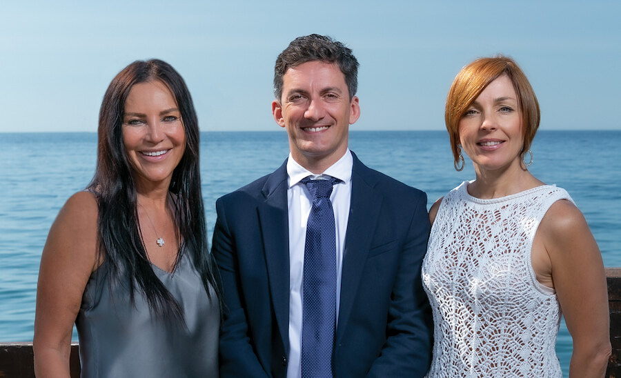 Three Panorama listings agents posing by the sea in a professional team portrait.