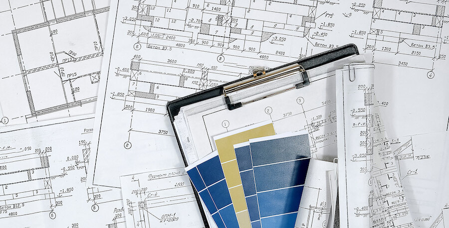 Architectural blueprints with building plans, colour samples and a clipboard used for construction and design planning.