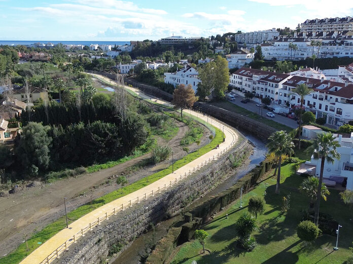 Luchtfoto van Marbella’s nieuwe rivierpromenade, met een geplaveid pad, leuningen en nabijgelegen woningen, en de Middellandse Zee in de verte.