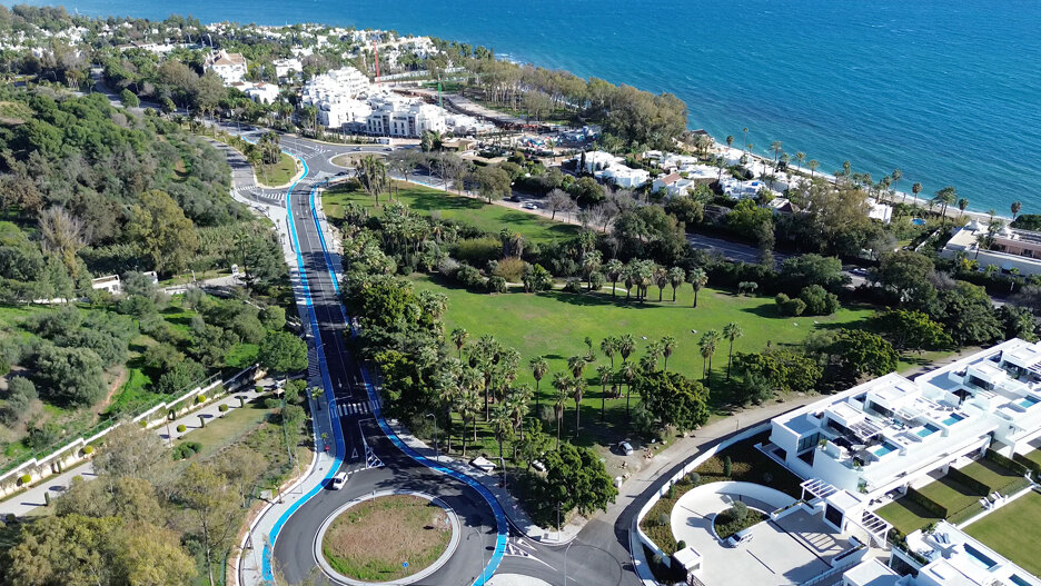 Luchtfoto van het kustgebied van Marbella met een aangelegd park, met palmbomen omzoomde lanen, moderne woongebouwen en de Middellandse Zee op de achtergrond.