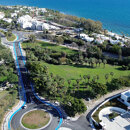 Vista aérea de la zona costera de Marbella, con un parque ajardinado, avenidas bordeadas de palmeras, edificios residenciales modernos y el mar Mediterráneo al fondo.