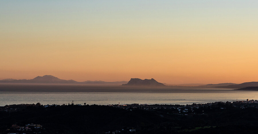 Sunset view over the Mediterranean with distant mountain silhouettes and coastline on the horizon, seen from above Marbella.