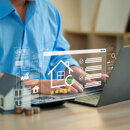 Persona utilizando un portátil para gestionar anuncios inmobiliarios, con iconos digitales del sector, valoraciones y el símbolo de una vivienda en pantalla, que representan la evaluación y gestión online de propiedades.