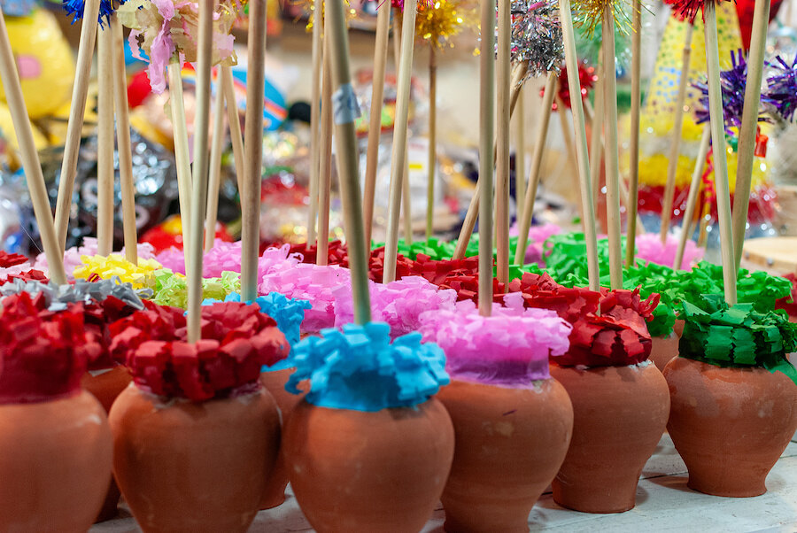 Row of small clay pots filled with bright tissue paper and wooden sticks, part of colourful traditional Christmas decorations in Spain.
