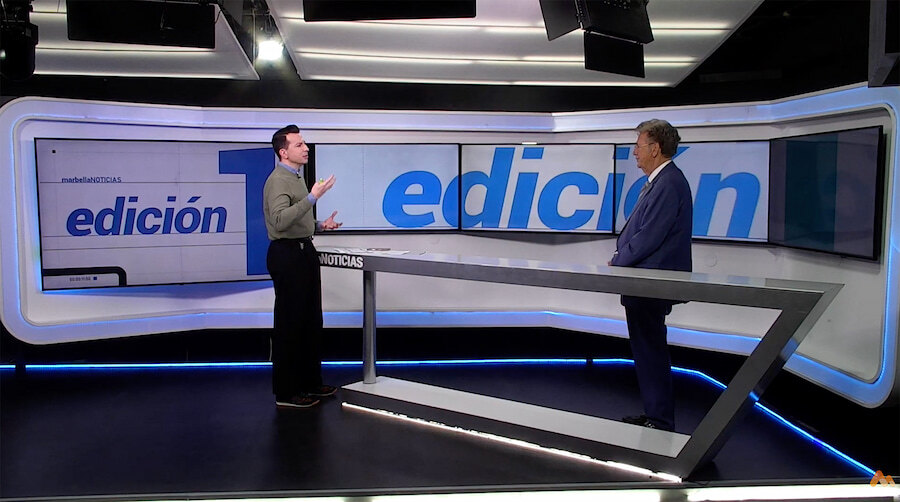 Christopher Clover being interviewed in the RTV Marbella news studio, standing beside the presenter on the “Edición” set.