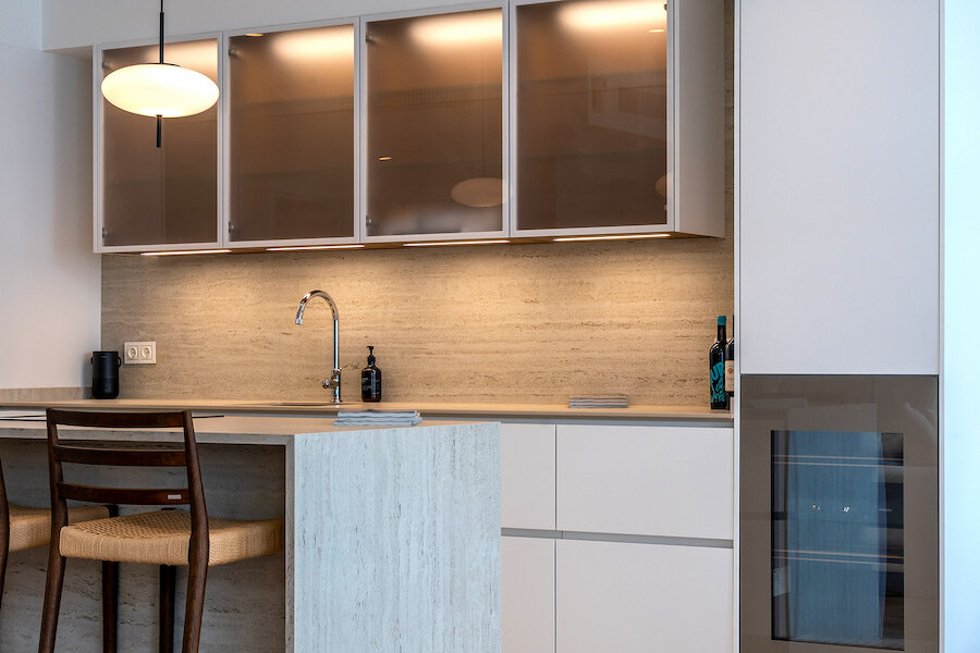Detail of the modern kitchen at Casa Marisal, featuring a stone island, soft-lit frosted cabinets, sleek fixtures, and integrated appliances.