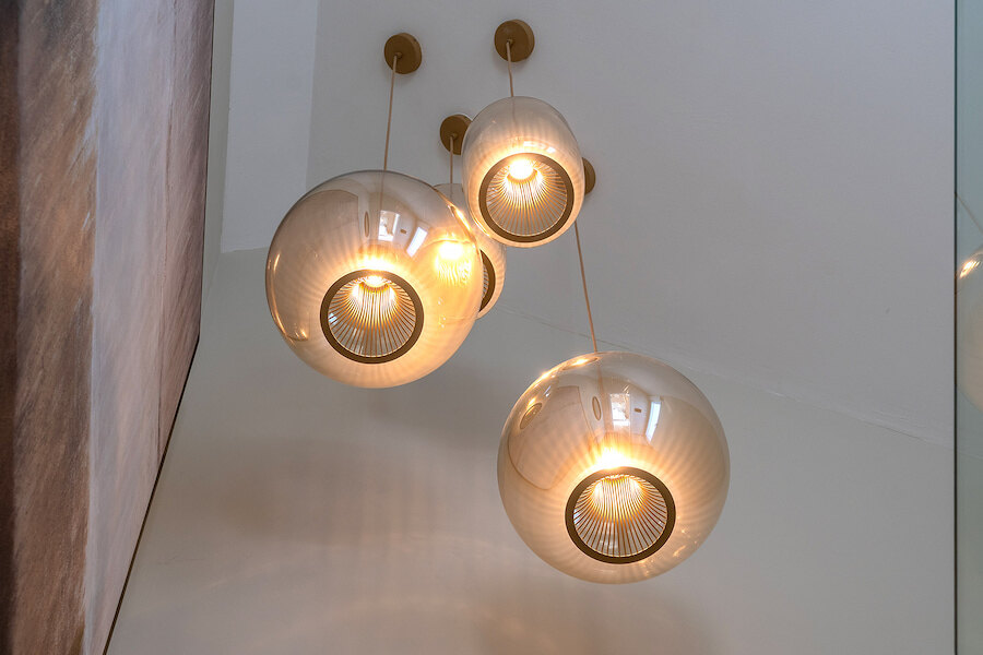 Close-up of modern spherical pendant lights at Casa Marisal, featuring warm illumination and glass globes suspended from the ceiling.
