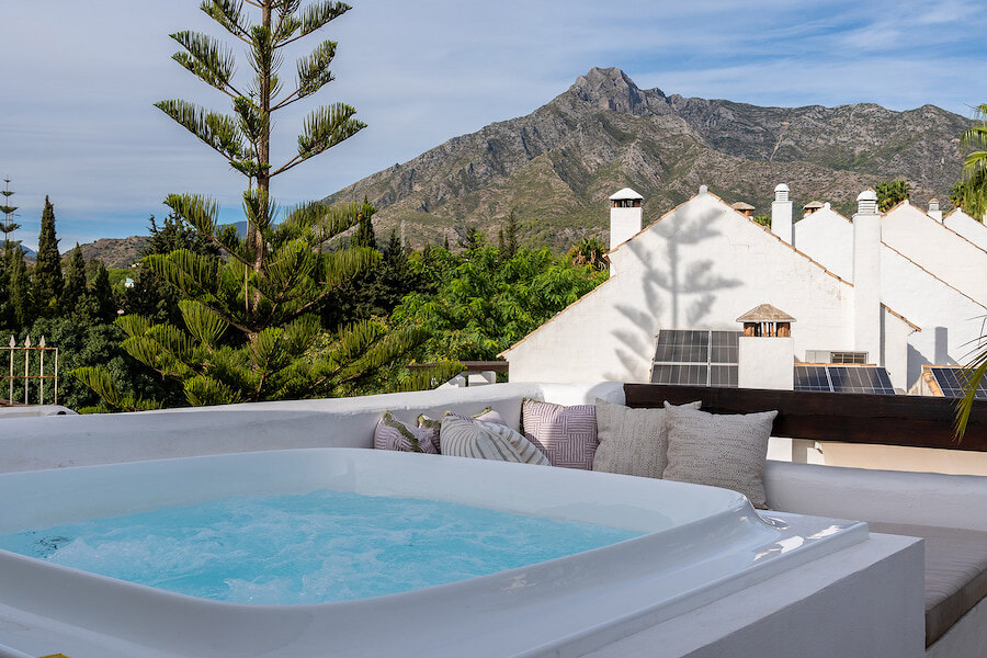 Rooftop jacuzzi at Casa Marisal with mountain views of La Concha, surrounded by lush greenery and white Mediterranean-style rooftops.