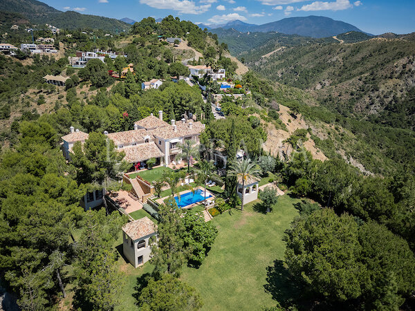 Immobilien in Marbella. Luftaufnahme der Villa Goya, einer großen mediterranen Villa auf einem Hügel mit Pool, Gästehäusern und weitläufigem Rasen, umgeben von Kiefern und Bergen mit Panoramablick über das Tal.