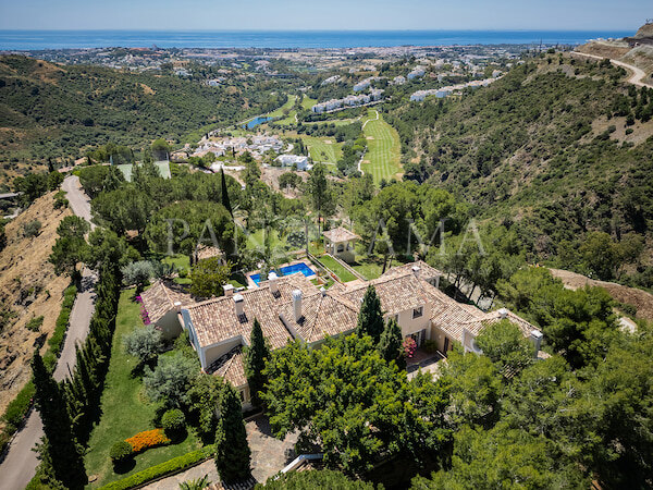 Vista aérea de Villa Goya PANR-15624, una villa de estilo mediterráneo con piscina y jardines paisajistas, con vistas a un verde valle de golf que se extiende hasta el mar Mediterráneo en la lejanía.