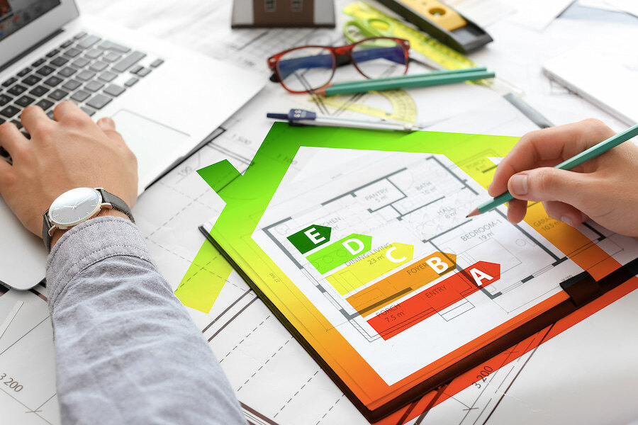 Architect working on house plan with energy efficiency rating chart from A to E.