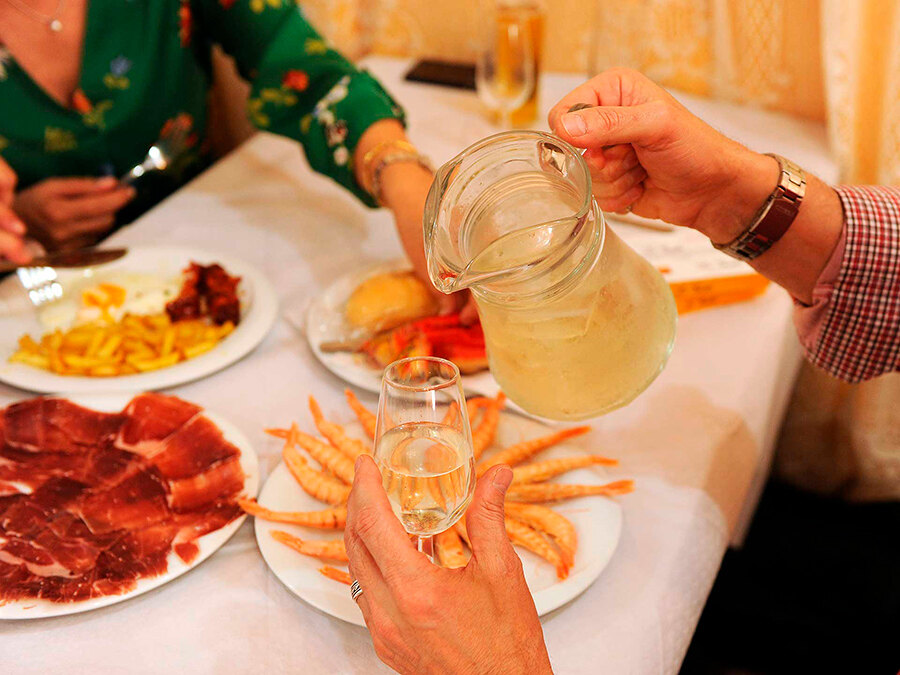Serving a pitcher of rebujito - cocktail made with sherry and lemon-lime soda, often with mint - at a table inside a caseta