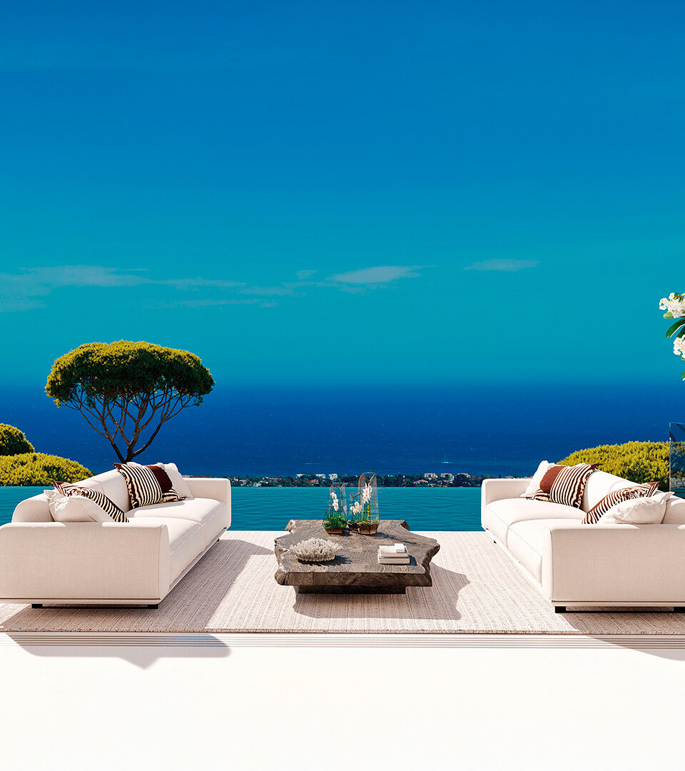Luxuriöse Außenterrasse mit weißen Sofas, einem Infinity-Pool und Panoramablick auf das Mittelmeer und üppiges Grün unter einem klaren blauen Himmel.